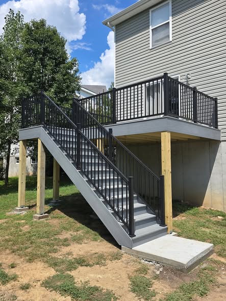 Cape Cod Grey composite deck with black aluminum handrails and a full set of composite stairs down to the concrete pad by B&R Construction