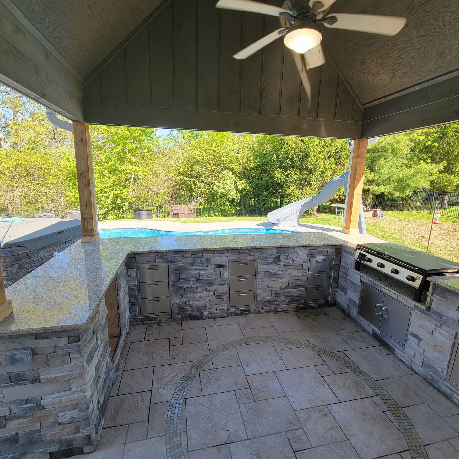 Griddle and grill side looking out over the pool — new 6×6 rough-cut cedar posts under the covered roof by B&R Construction