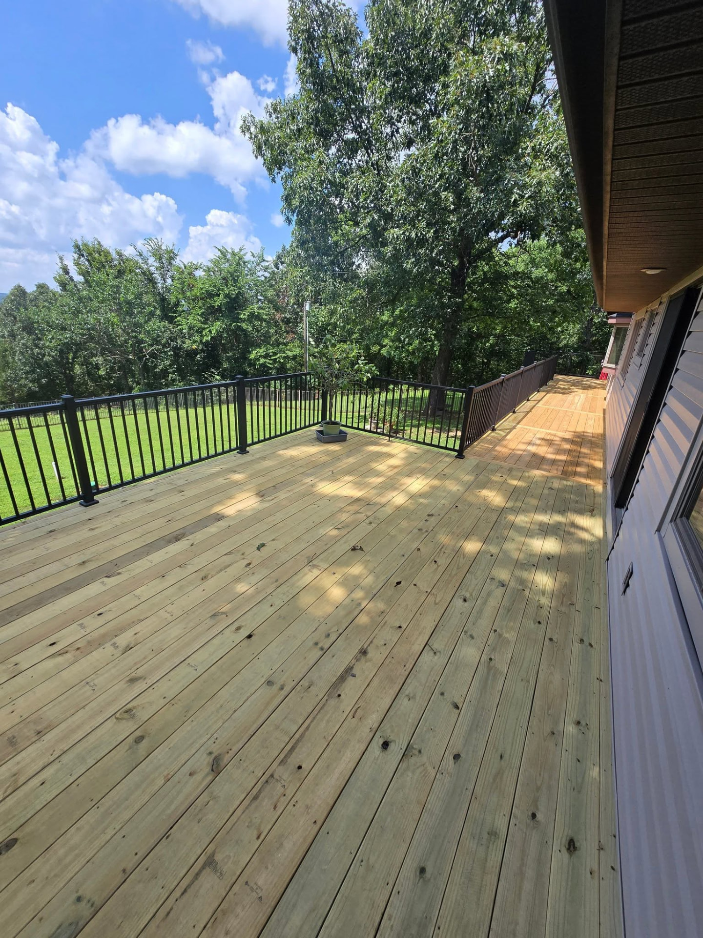 New treated decking wrapping the corner with black aluminum handrailing, looking out over the backyard by B&R Construction