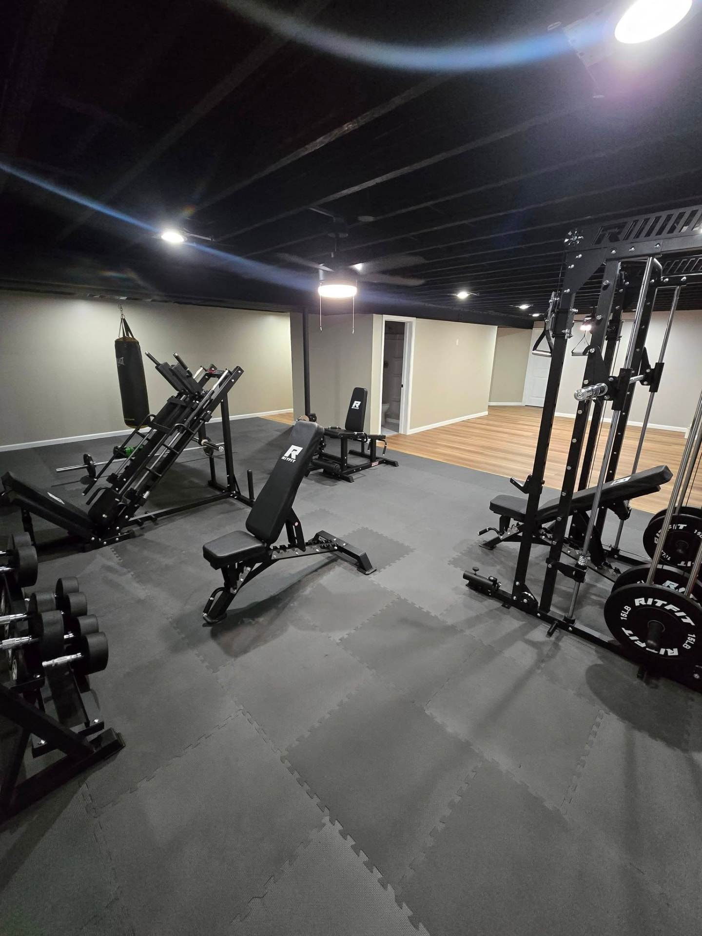 Basement home gym with mirrored walls and rubber flooring by B&R Construction