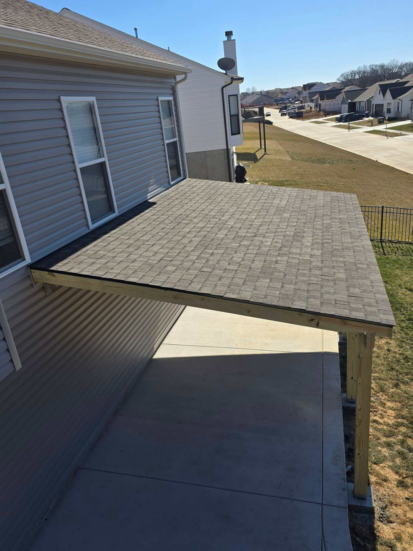 Shingled lean-to roof tying into the house, keeping the pad dry in any weather by B&R Construction