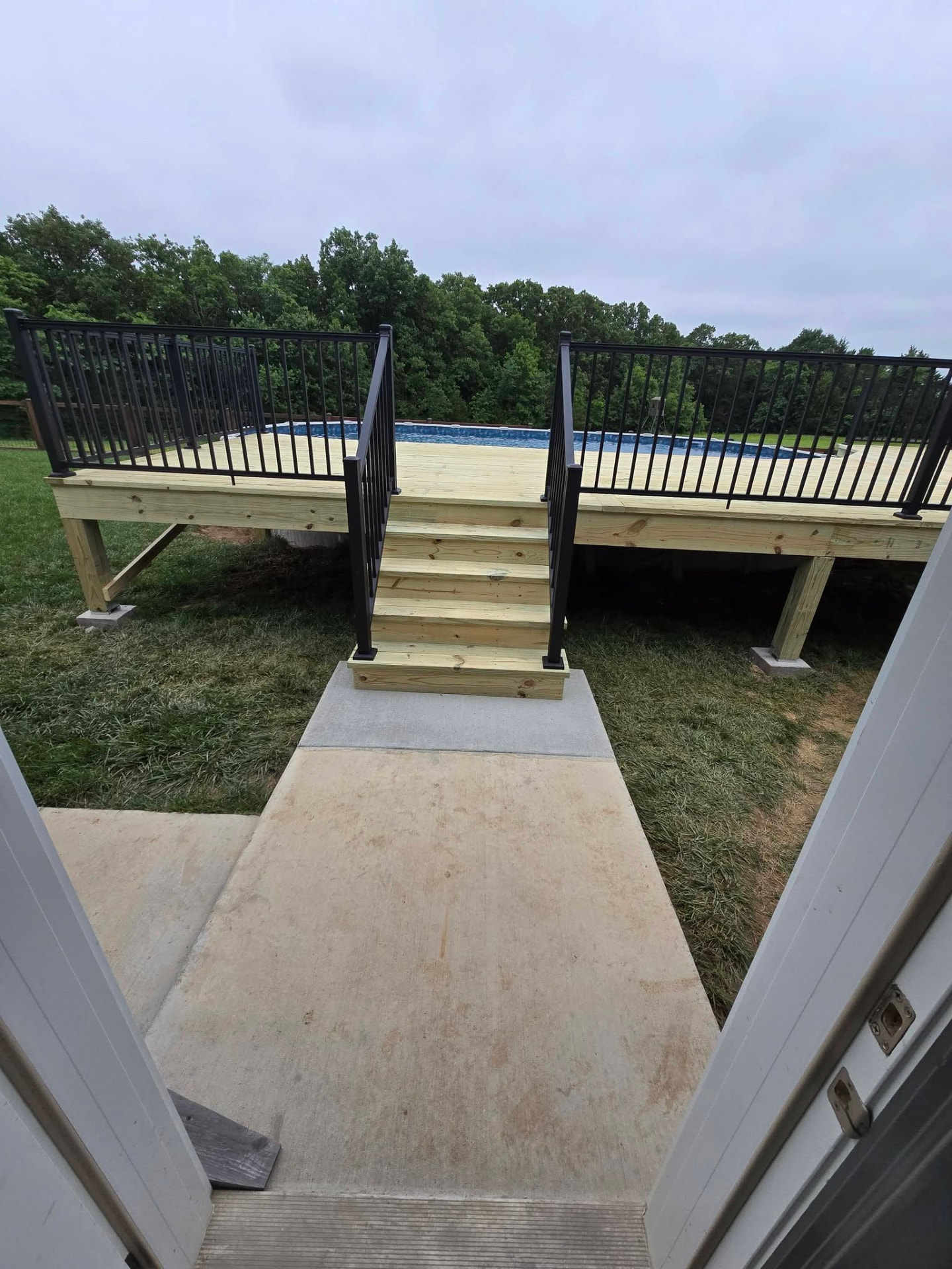 Treated deck stairs with handrail down to the concrete pad by B&R Construction