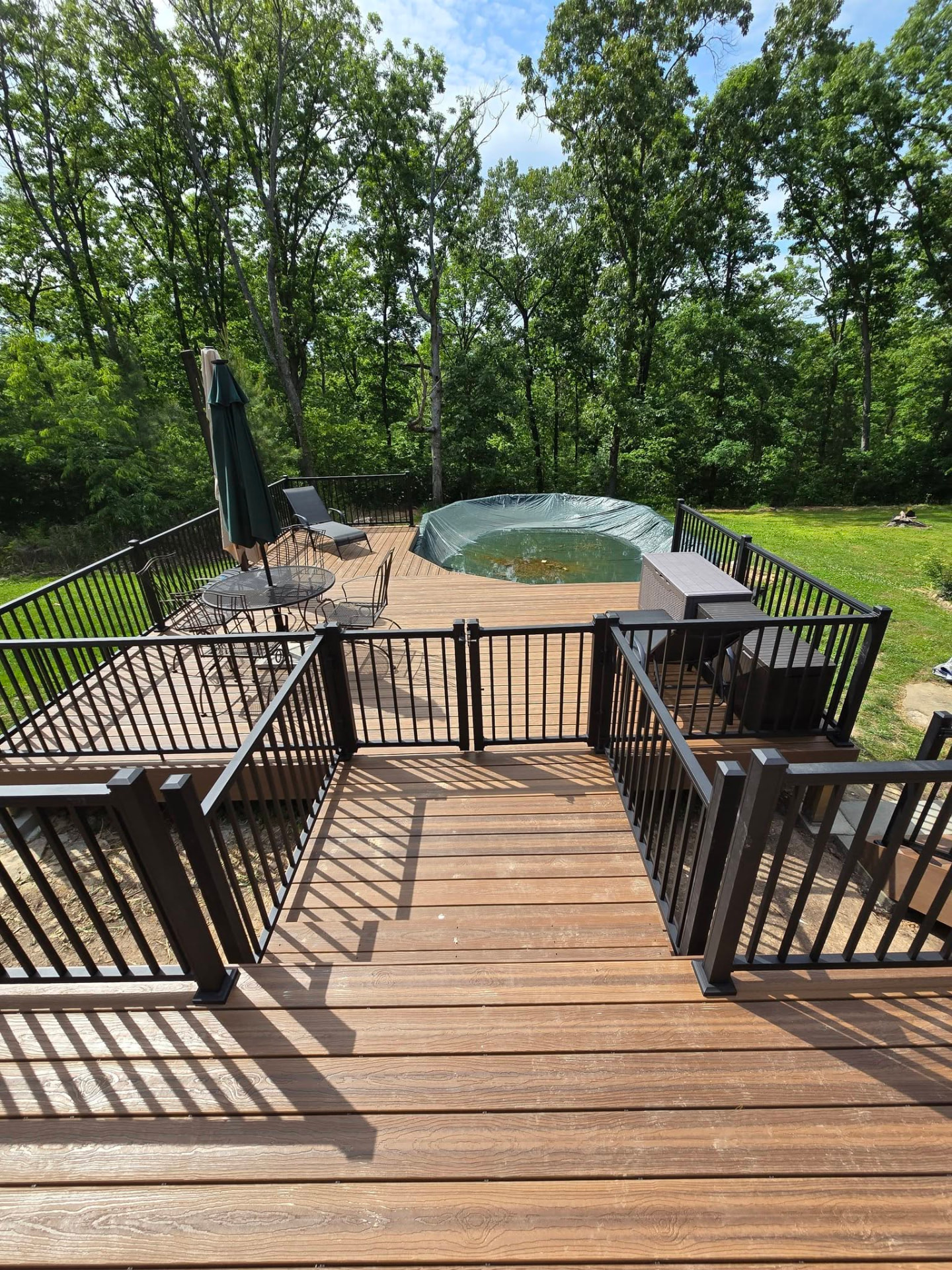 Pool-side seating area with a self-closing gate in the black aluminum handrail for safe pool access by B&R Construction