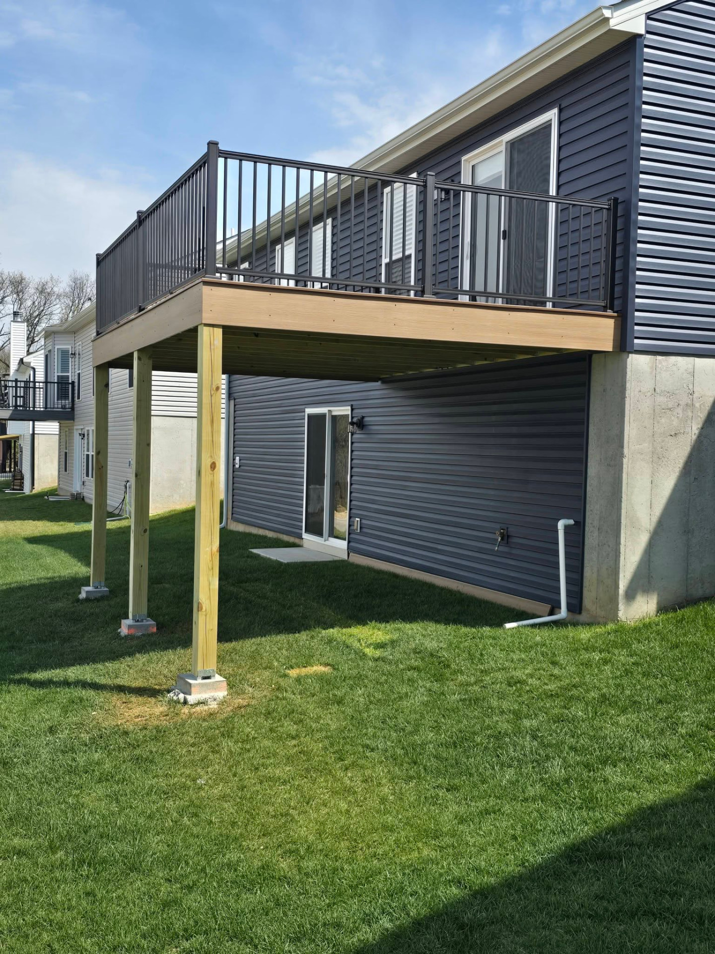 New-build second-story deck on posts set in concrete footings, with black aluminum handrails by B&R Construction