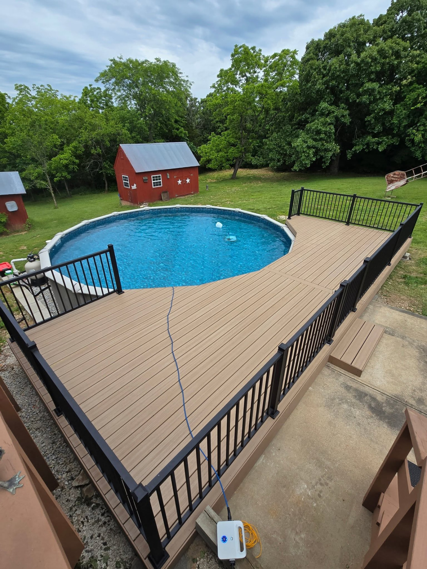 Maintenance-free composite pool deck with black aluminum handrails, built around the above-ground pool by B&R Construction