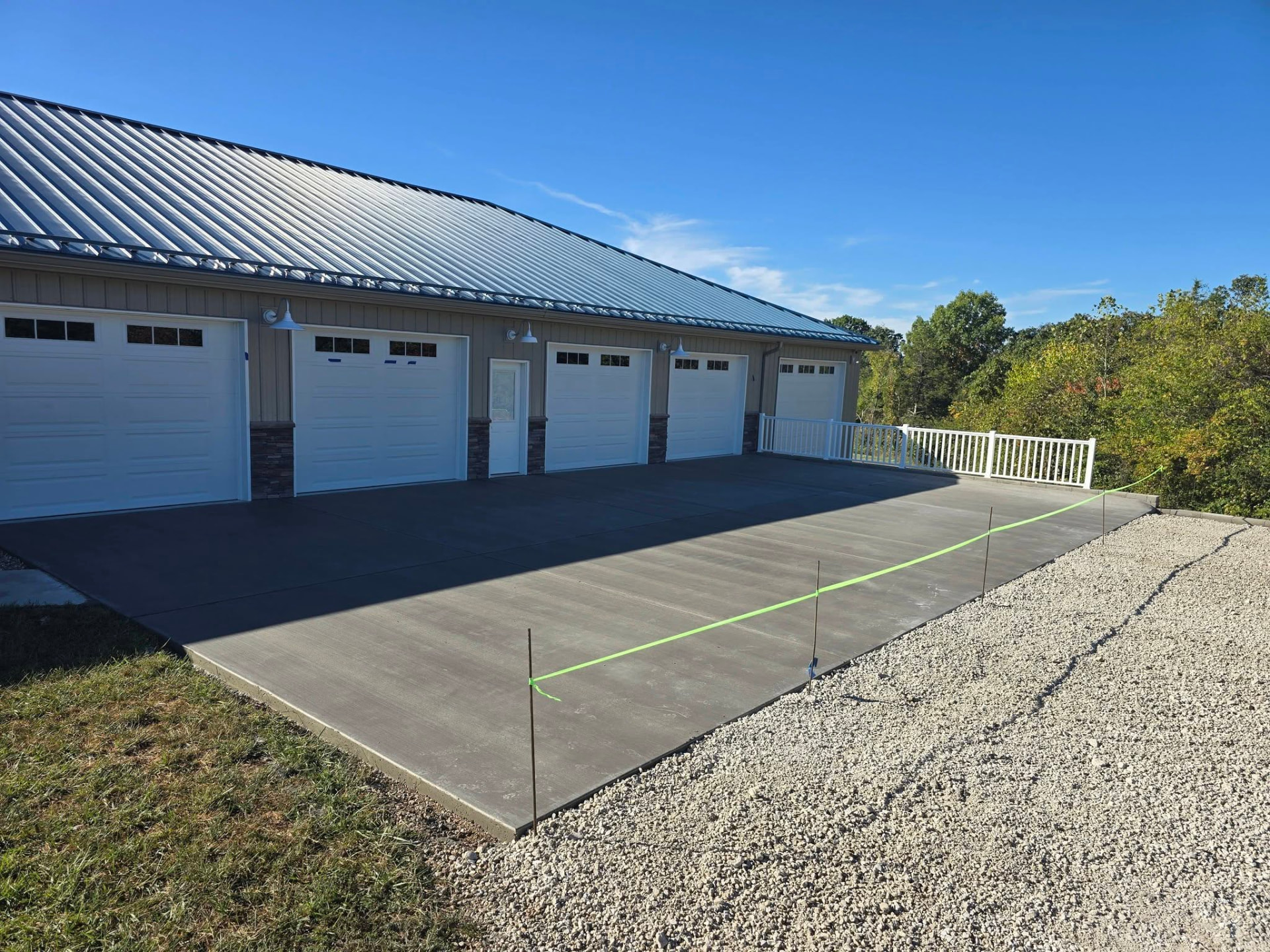 52' × 27' broom finish concrete pad in front of the garage bays, edged with white rail by B&R Construction