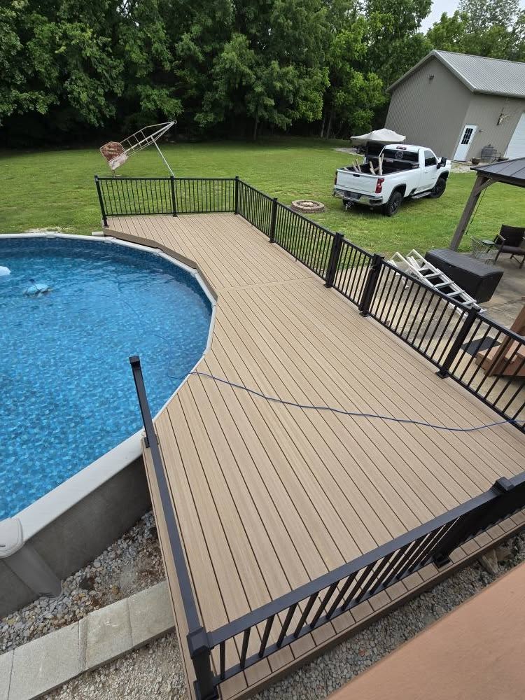 Composite pool deck boards wrapping the pool with black aluminum handrails, seen from above by B&R Construction