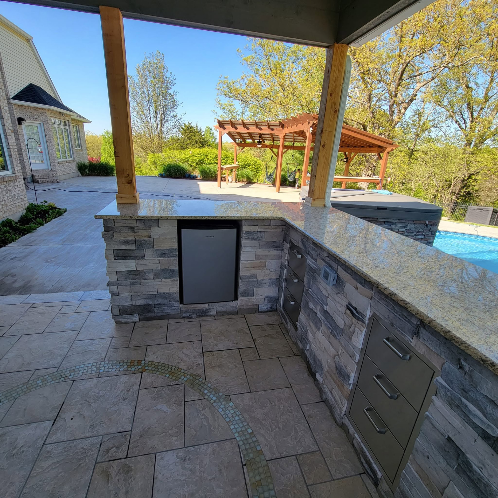 Bar seating with a stainless mini fridge built into the granite-topped island by B&R Construction