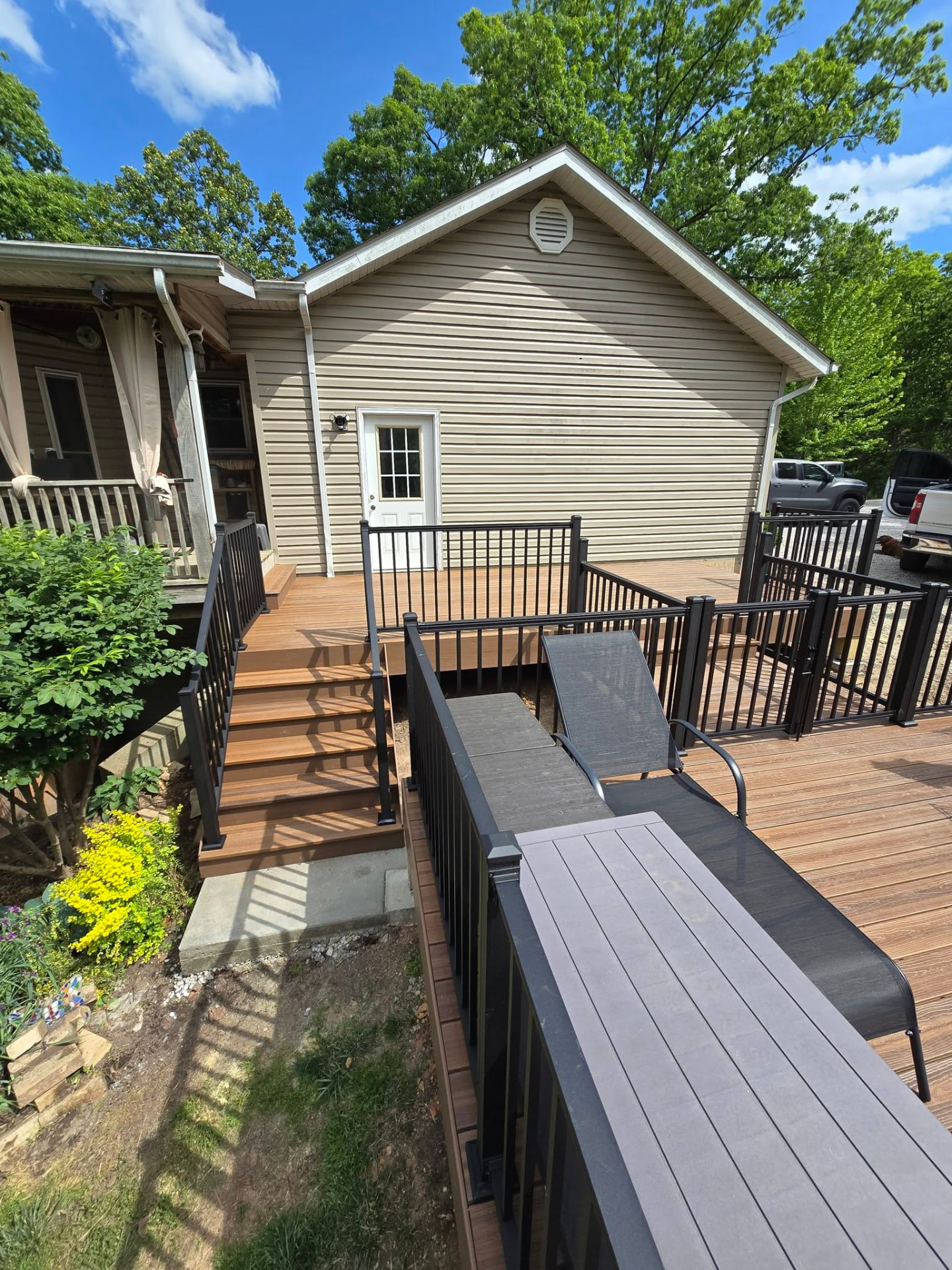 Stairs from the house down onto the composite pool deck, with the lower level and loungers beyond by B&R Construction