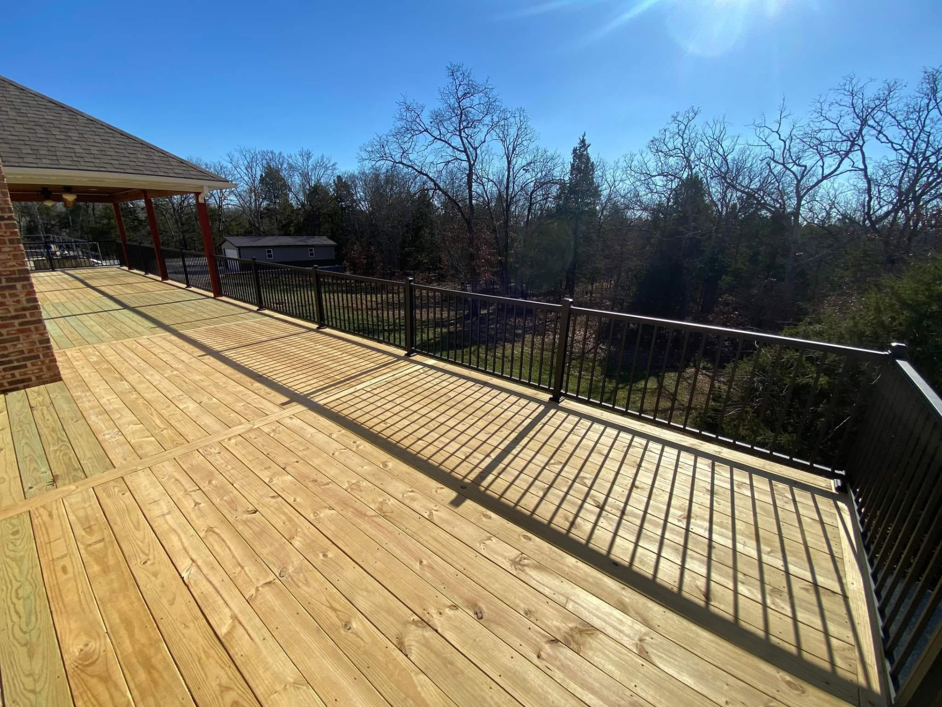 The finished treated deck surface with maintenance-free black aluminum handrails by B&R Construction