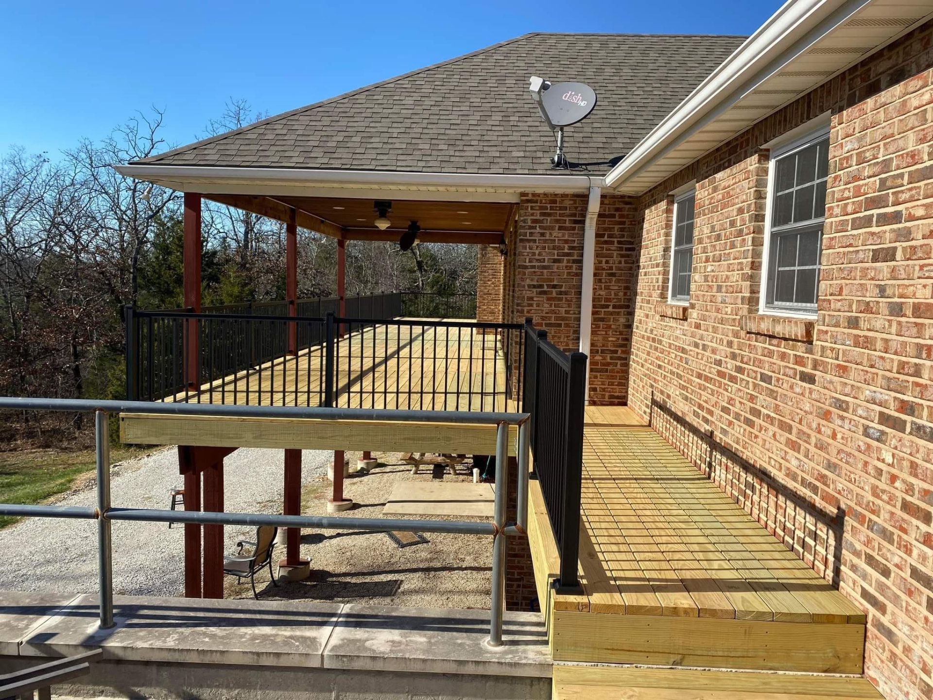 Fresh treated decking and black aluminum handrails along the walkway beside the house by B&R Construction
