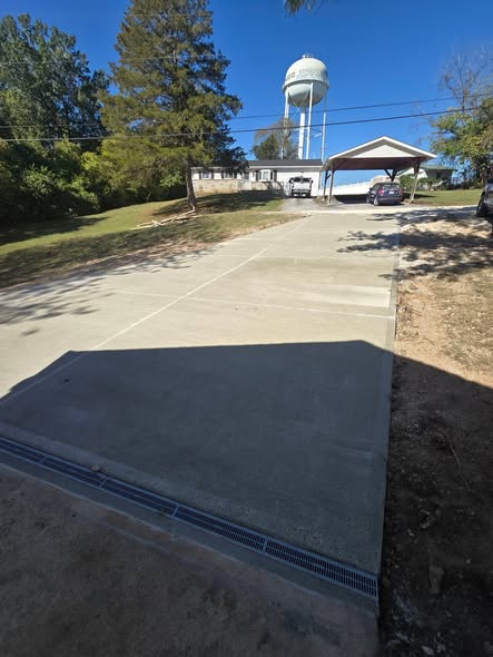 Broom-finish concrete driveway with a trench drain across the garage approach by B&R Construction